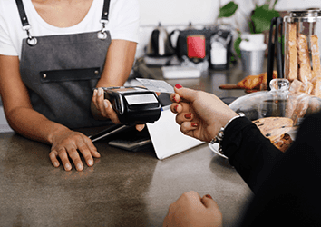 Restaurant worker taking card payment from a customer over counter