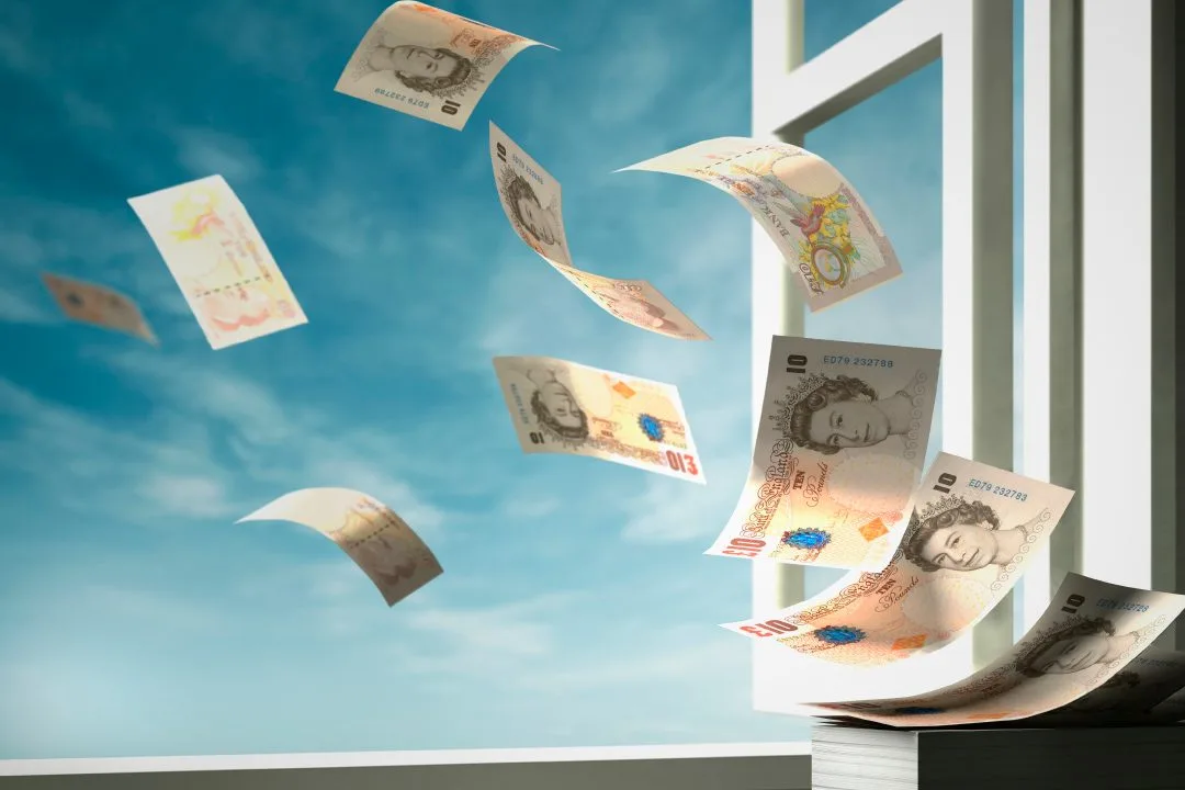 Image: Getty Images UK bank notes flying through a window