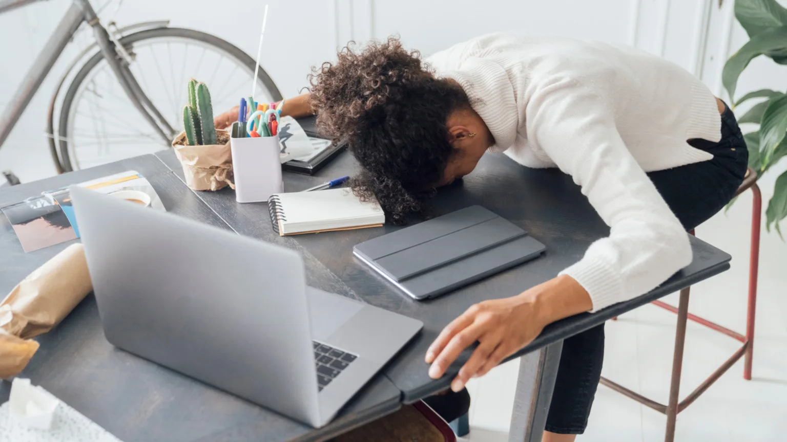 Image: Getty Images Tired woman with her head on the table in front of her opened laptop