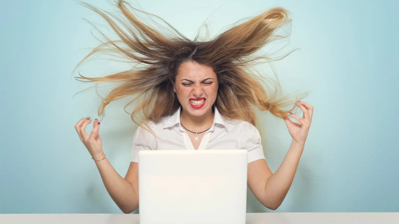 Image: Getty Images Angry woman with her hair flying sitting at a laptop