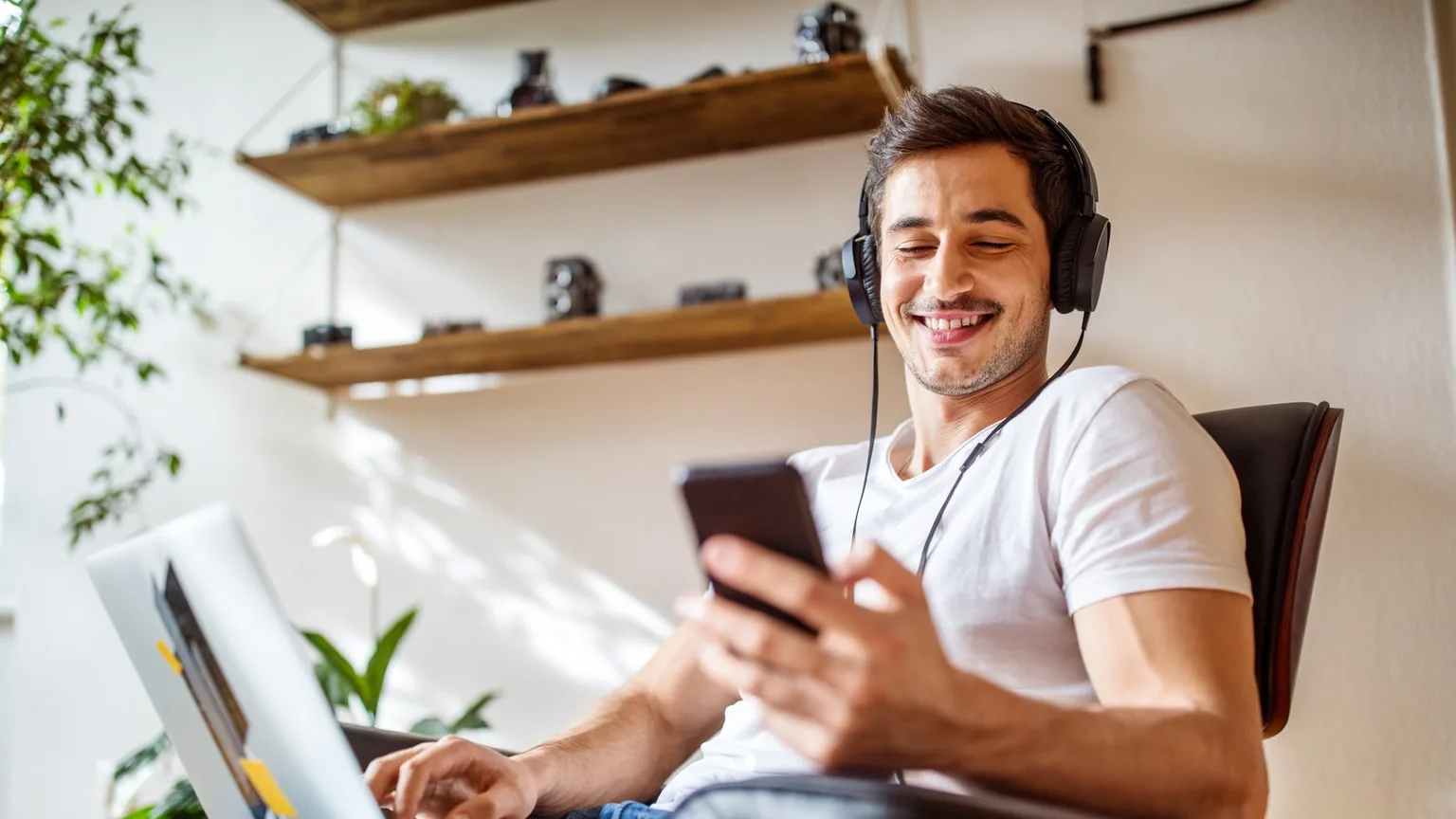Image: Getty Images Man wearing headphones listening to music from mobile phone