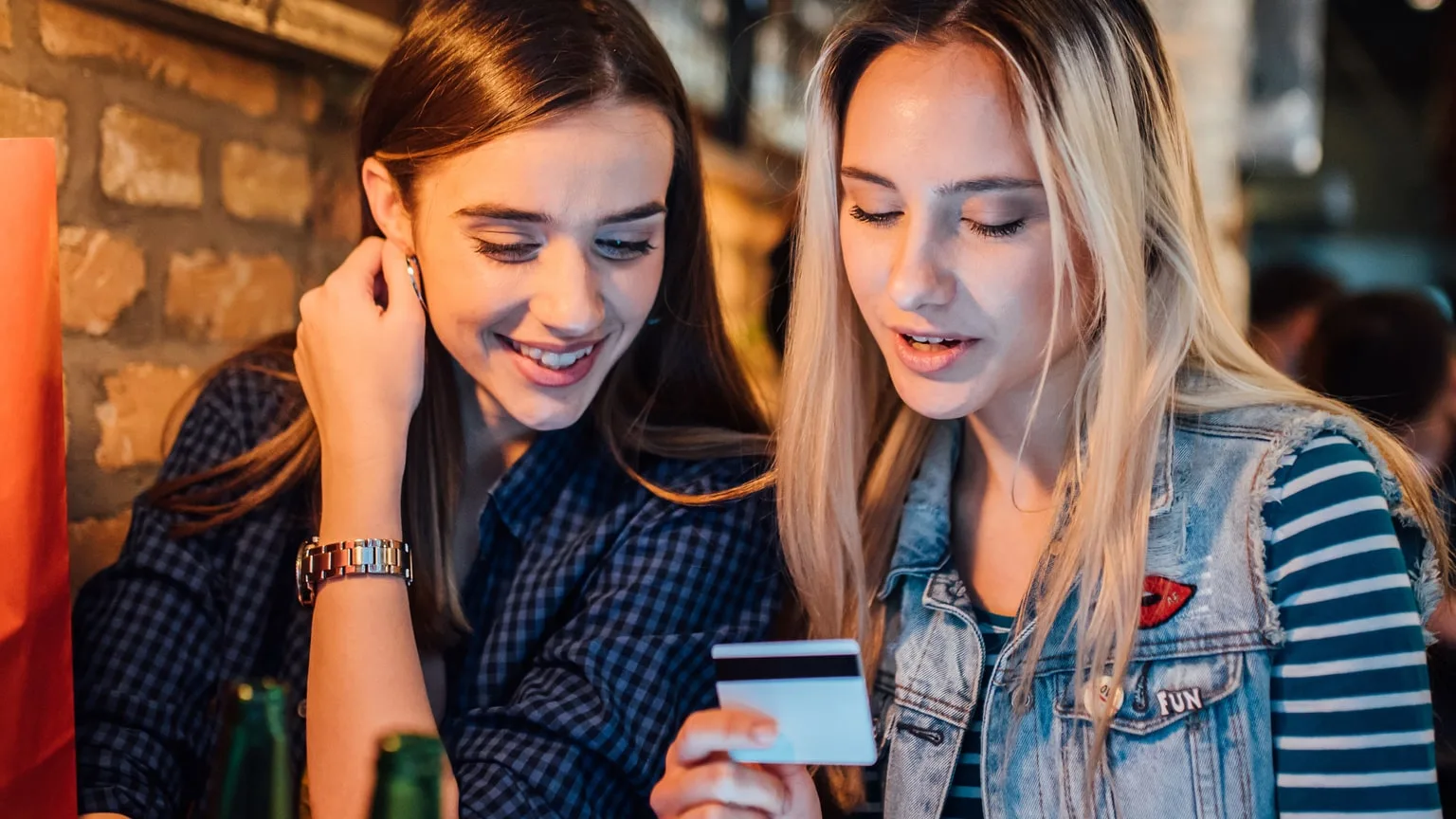 Image: Getty Images Two girls at a bar holding credit card about to drunk shop.
