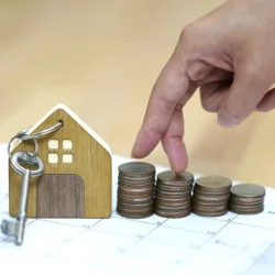 Image: Getty Images Fingers climbing stacks of coins near a toy house