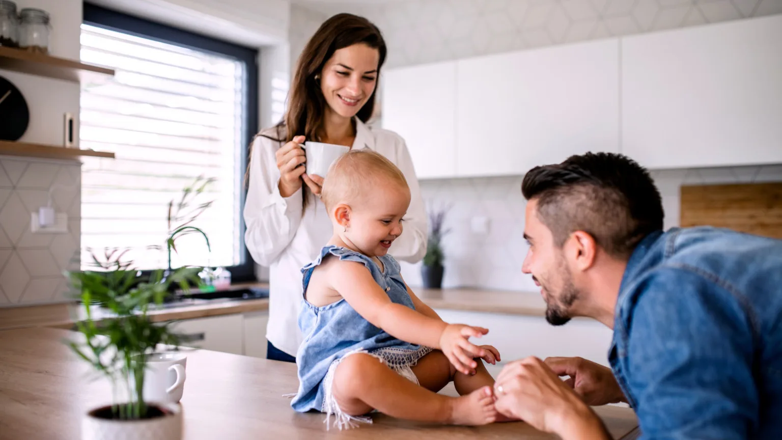 Image: Getty Images Young parents with smiling baby in kitchen