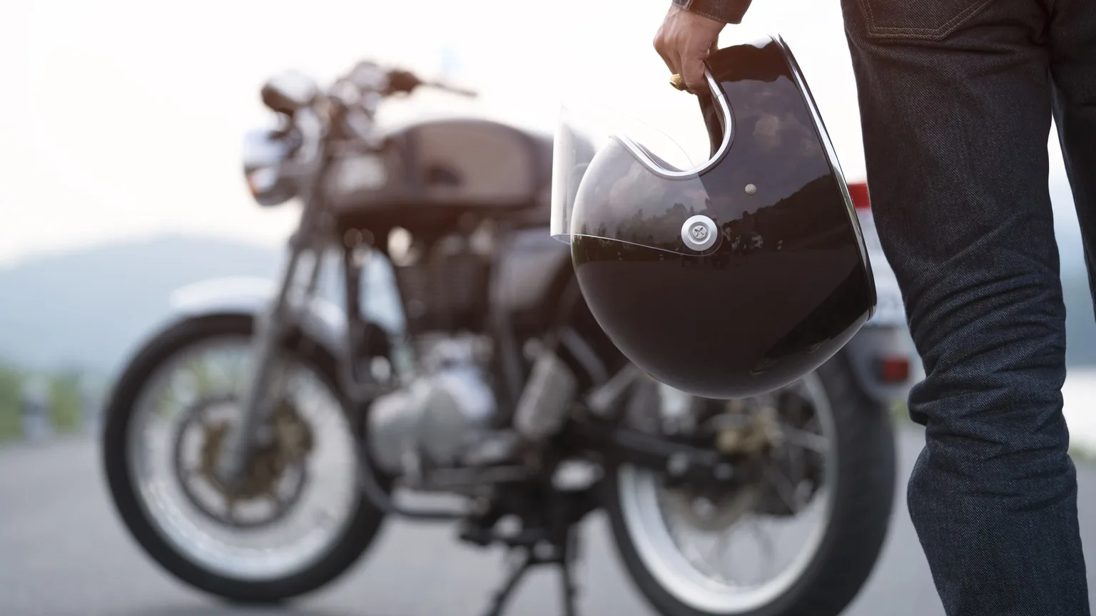 Image: Getty Images Man Holding Helmet Looking At Motorcycle