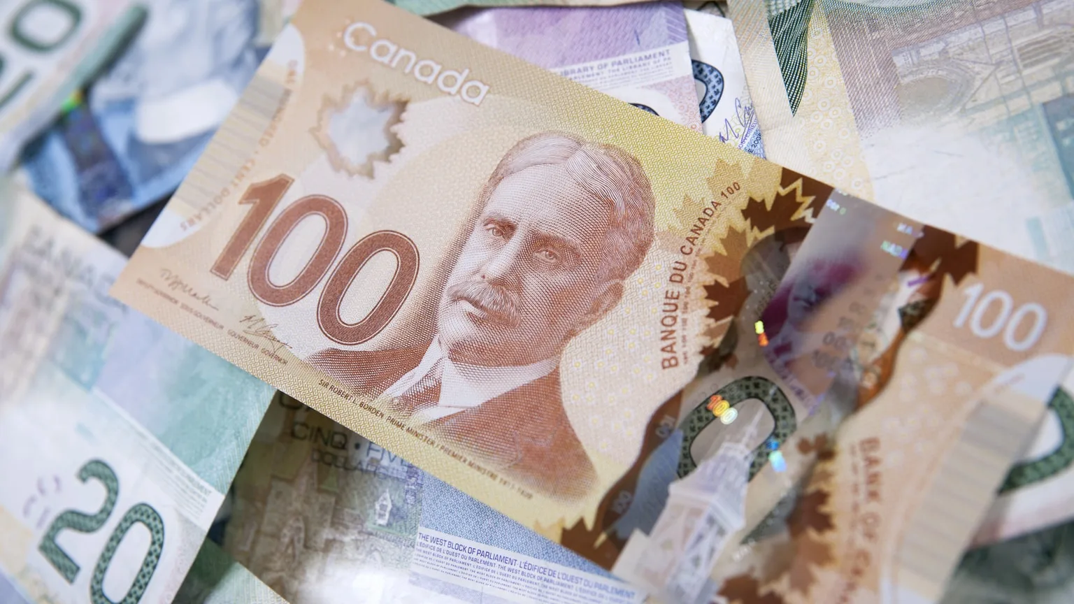 Image: Getty Images One hundred dollar bill on pile of Canadian money