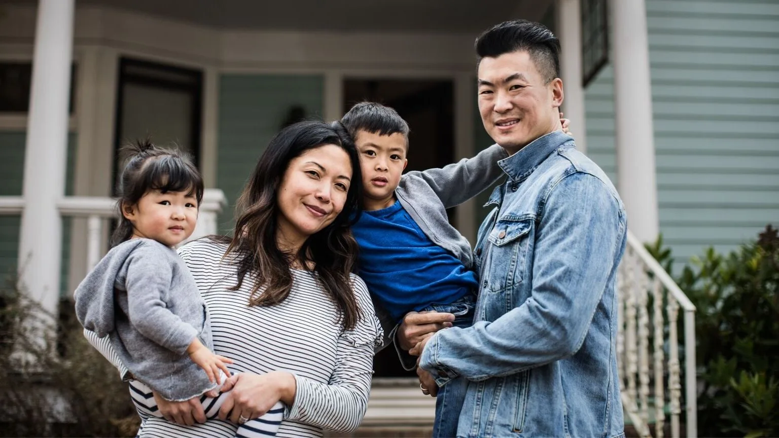 Image: Getty Images Family of four standing outside home.