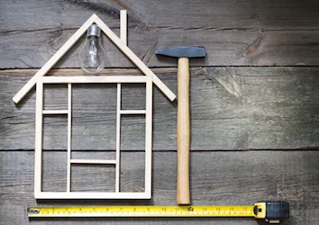 Hammer, measuring tape and wooden sticks shaped like a house