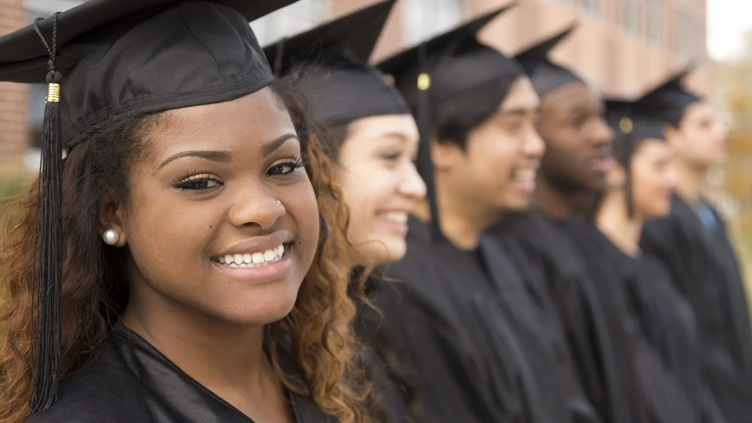 Image: Getty Images Smiling woman in row of graduates, high school, college, university