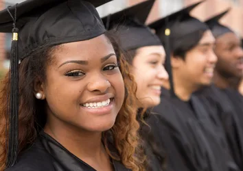 Smiling woman in row of graduates, high school, college, university