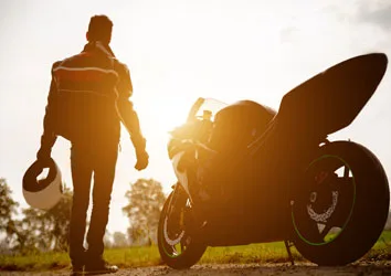 A motorcycle rider with his bike facing the sun