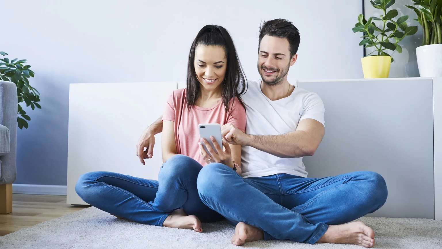 Smiling couple comparing loan options on a mobile phone