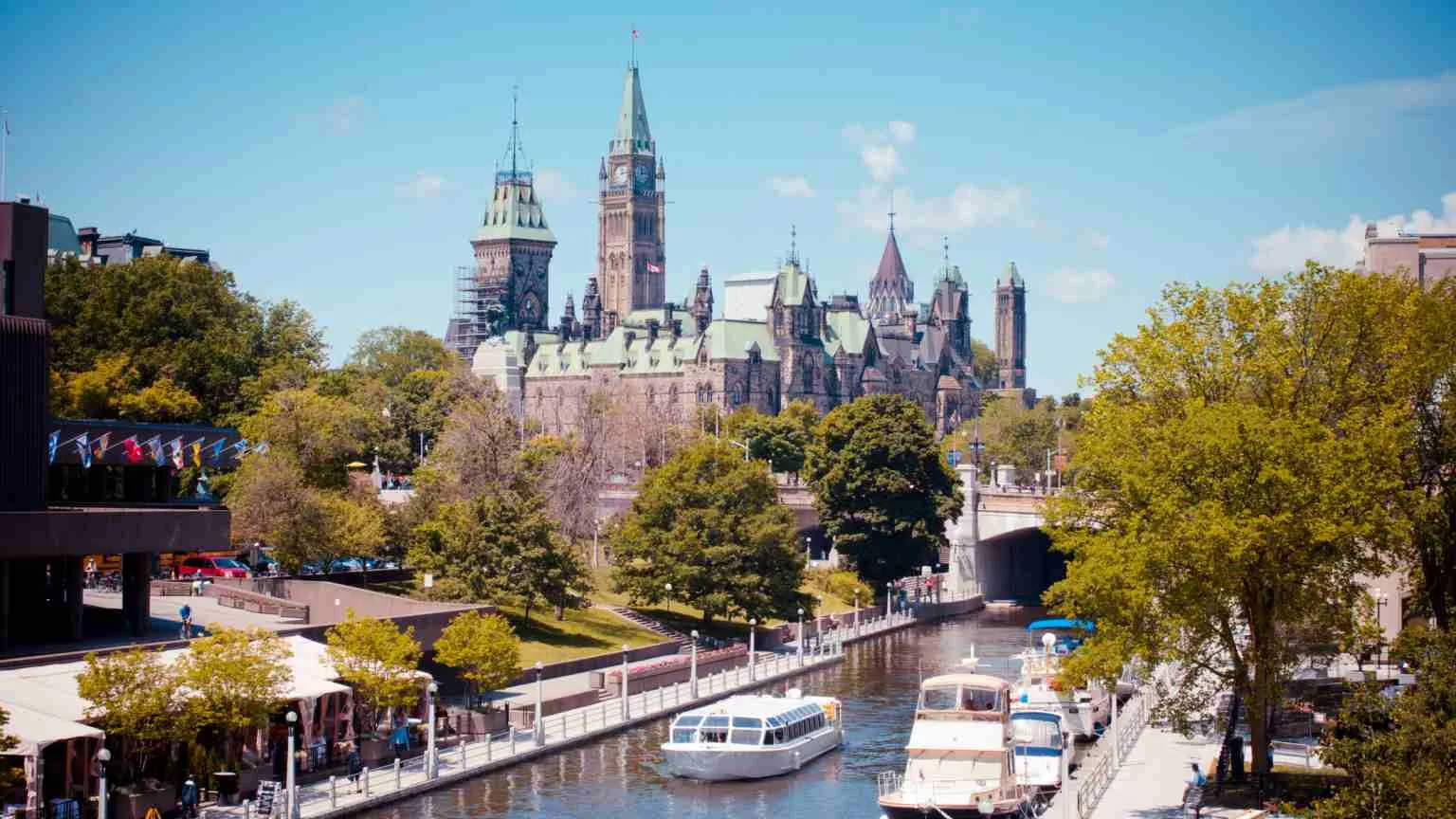 Image: Getty Images Summer day on Ottawa's historic Rideau Canal, with Canada's Parliament Buildings and Peace Tower looming in background and National Arts Centre to left.
