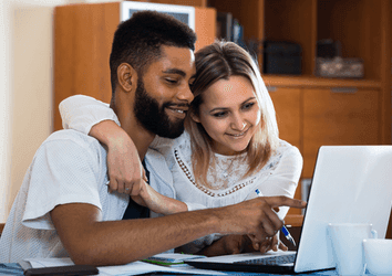 Young couple checking savings accounts in a laptop in a domestic interior