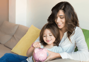 Mother and daughter putting coins into piggy bank