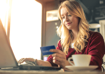 Young woman checking savings accounts in a laptop in a coffee shop