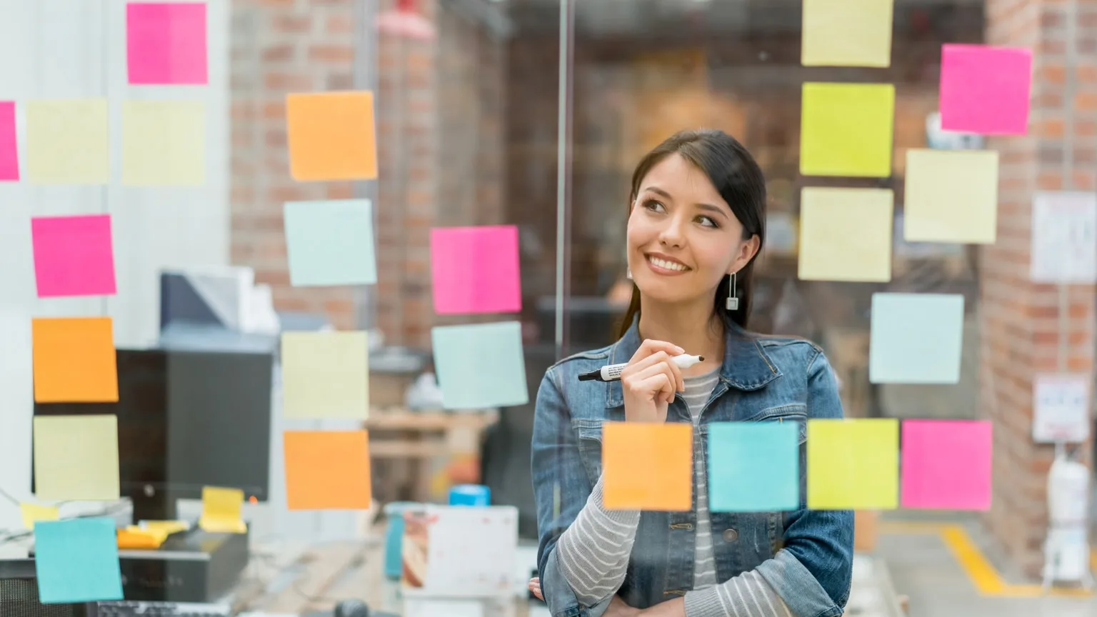 Image: Getty Images Smiling woman writing a marketing plan on sticky notes