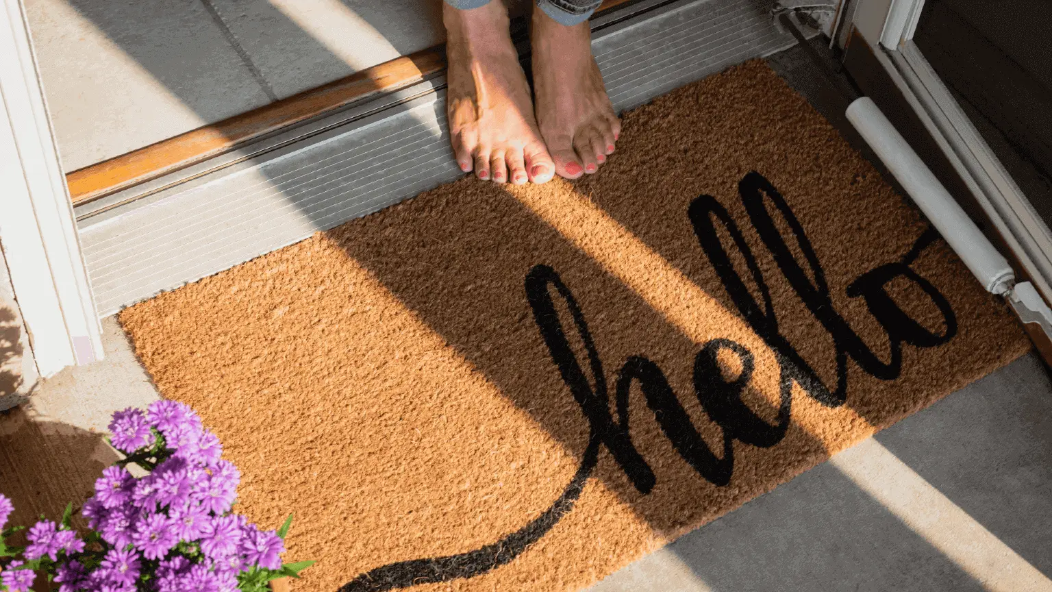 Image: iStock Low Section Of Woman Standing By Doormat With Hello Text